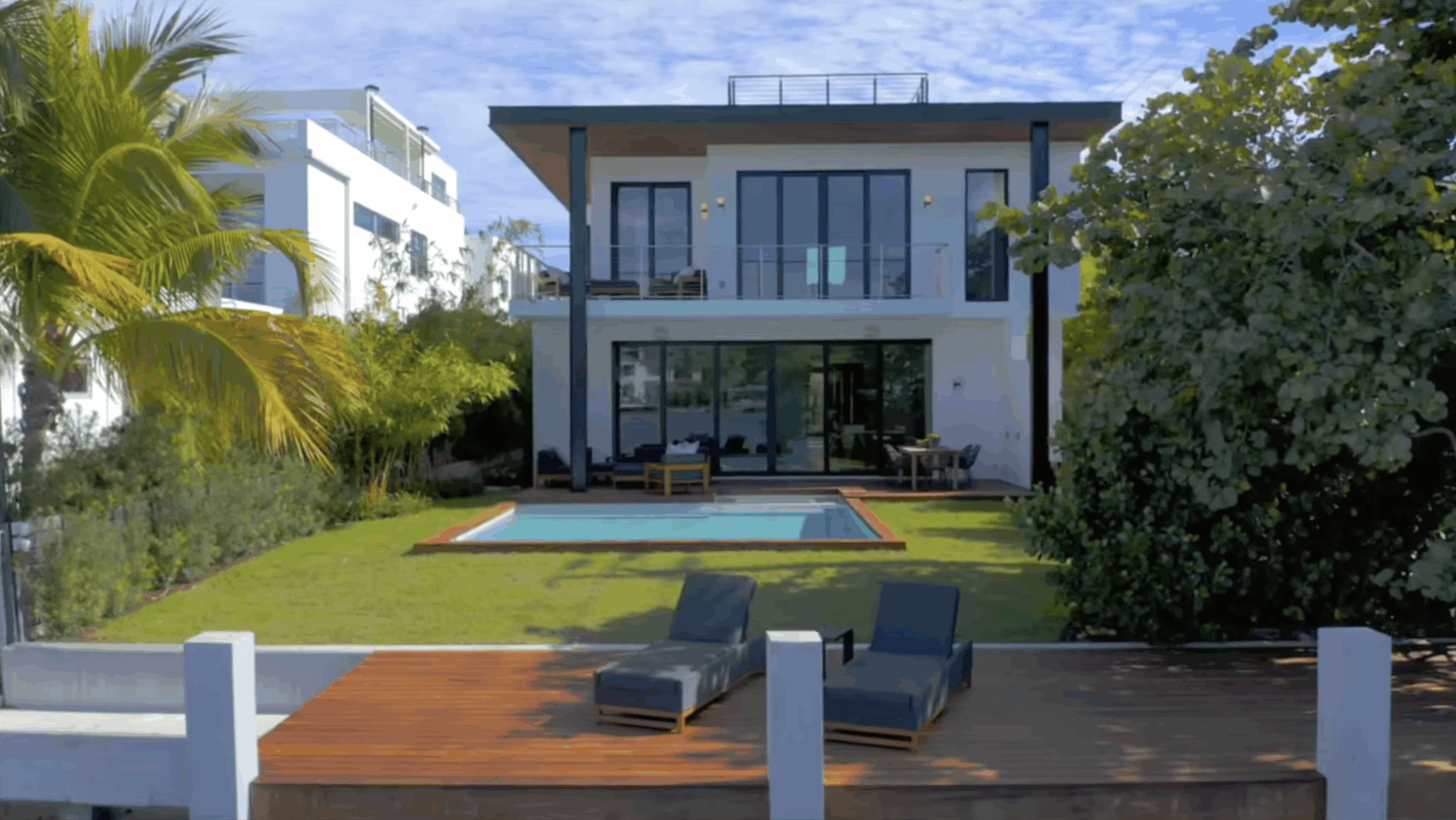 New luxury home construction in Miami. Highlighting the backyard on the inlet in Florida. Backyard includes a pool with impact sliding doors leading inside and balcony sliding hurricane impact doors.